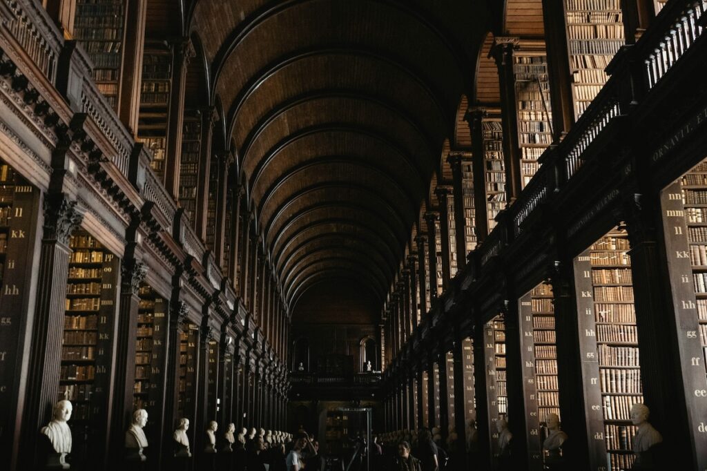 looking toward the ceiling of an ornate library with stacks of shelved books on either side of of the image