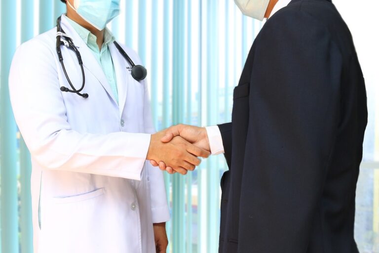 doctor shakes hands with a person in a suit