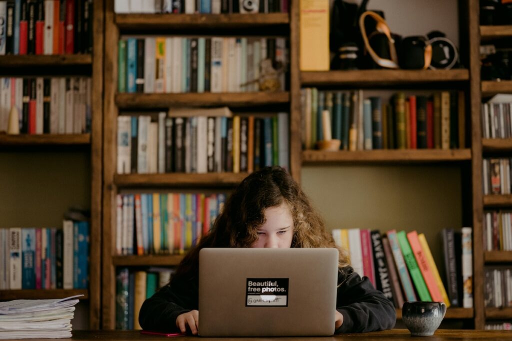 student reads laptop screen intently in a library setting