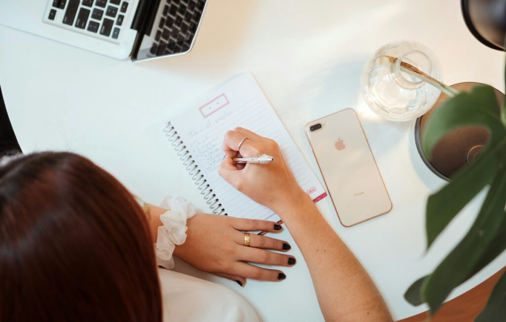 woman writing in notebook on desk