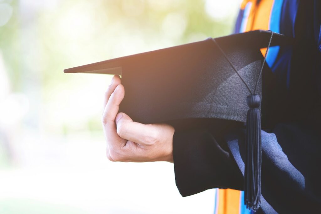 college graduate holds cap against their chest