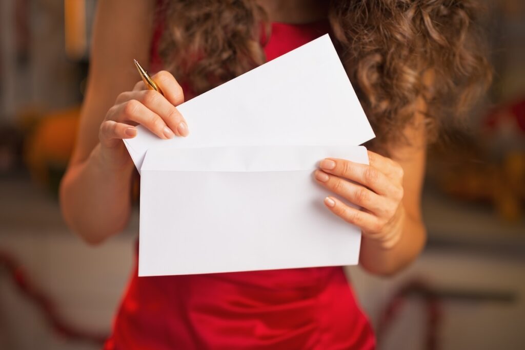 Closeup on woman in red dress takes a letter out of an envelope