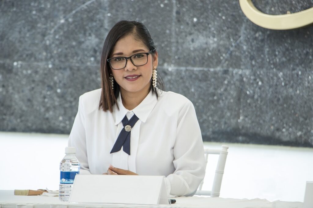 woman in professional clothing sits at the far side of a desk
