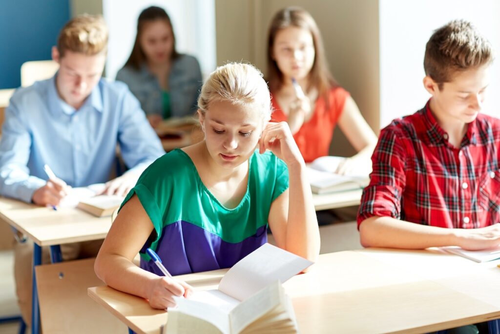 group of students with books writing school test