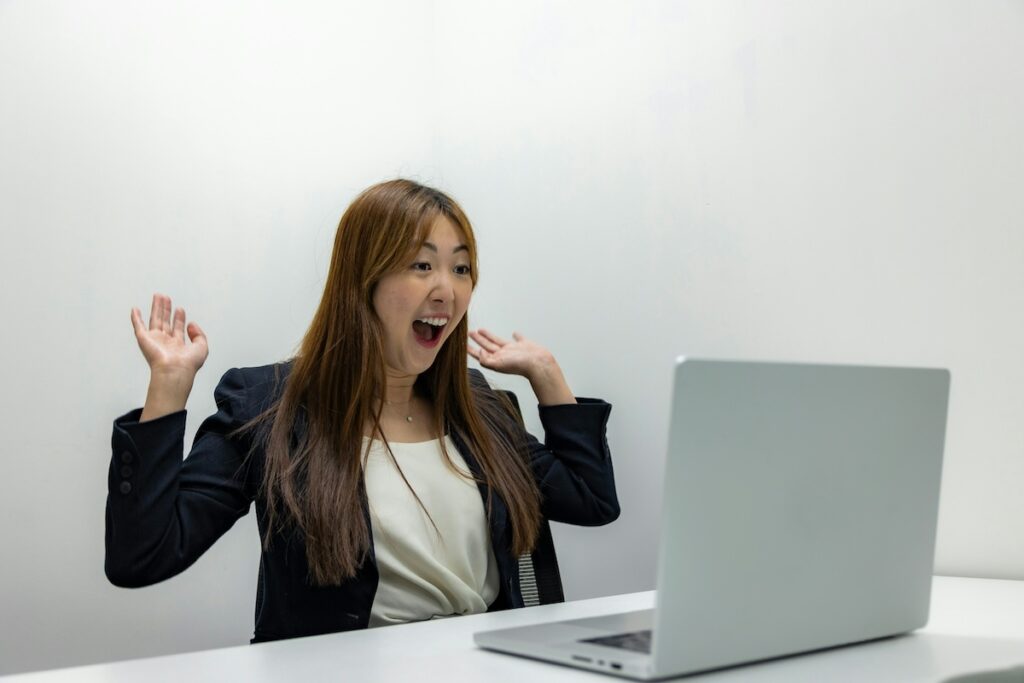 female student looks excited while reading something on laptop screen