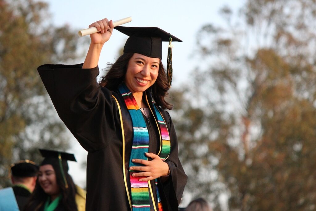 young woman in graduate cap and gown looking excited