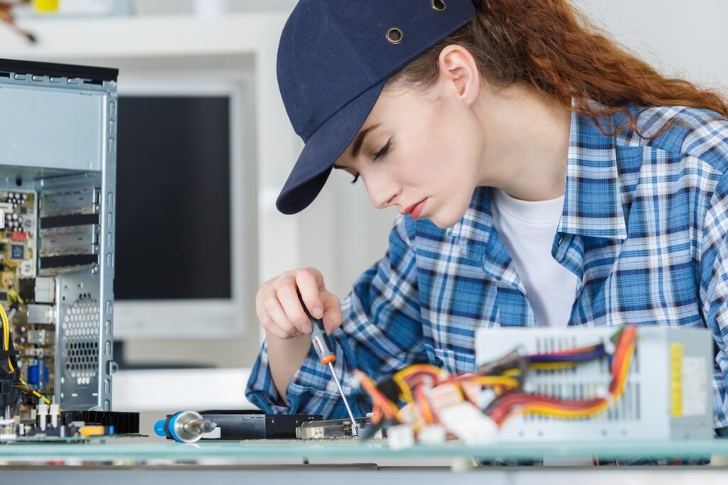 young woman fixing a desktop computer seated at a table
