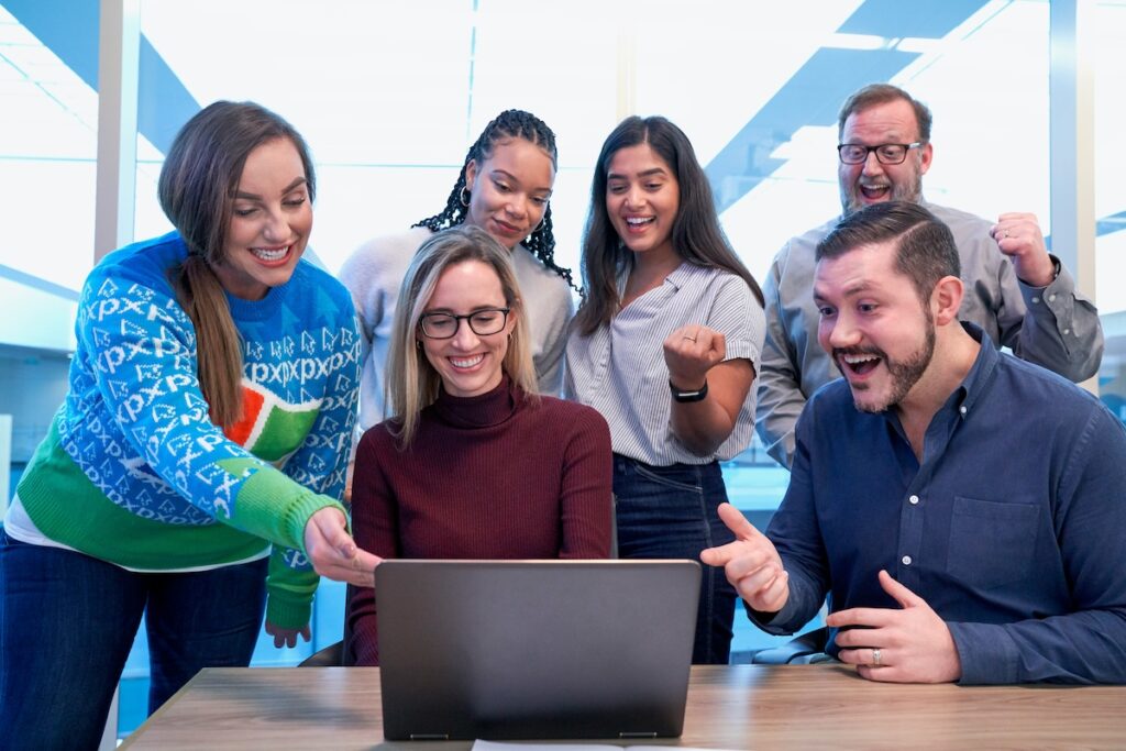 group of students and peers gather around a laptop