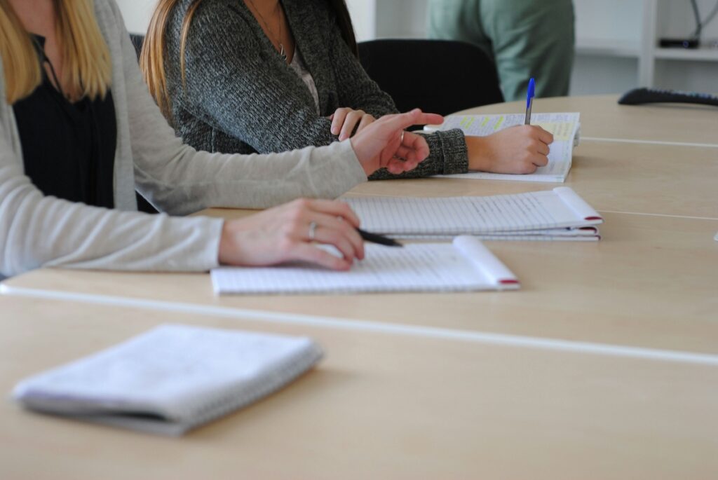 students sit at a table writing in notepads