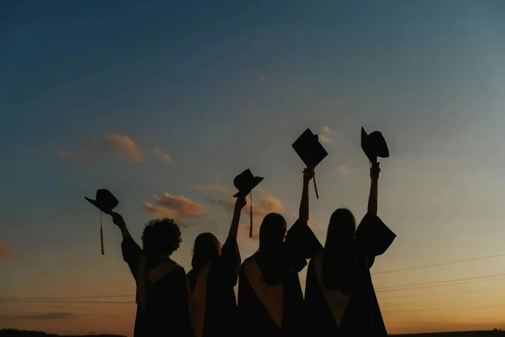 Boston University Notable Alumni: Silhouette of recent graduates throwing their caps in the air.
