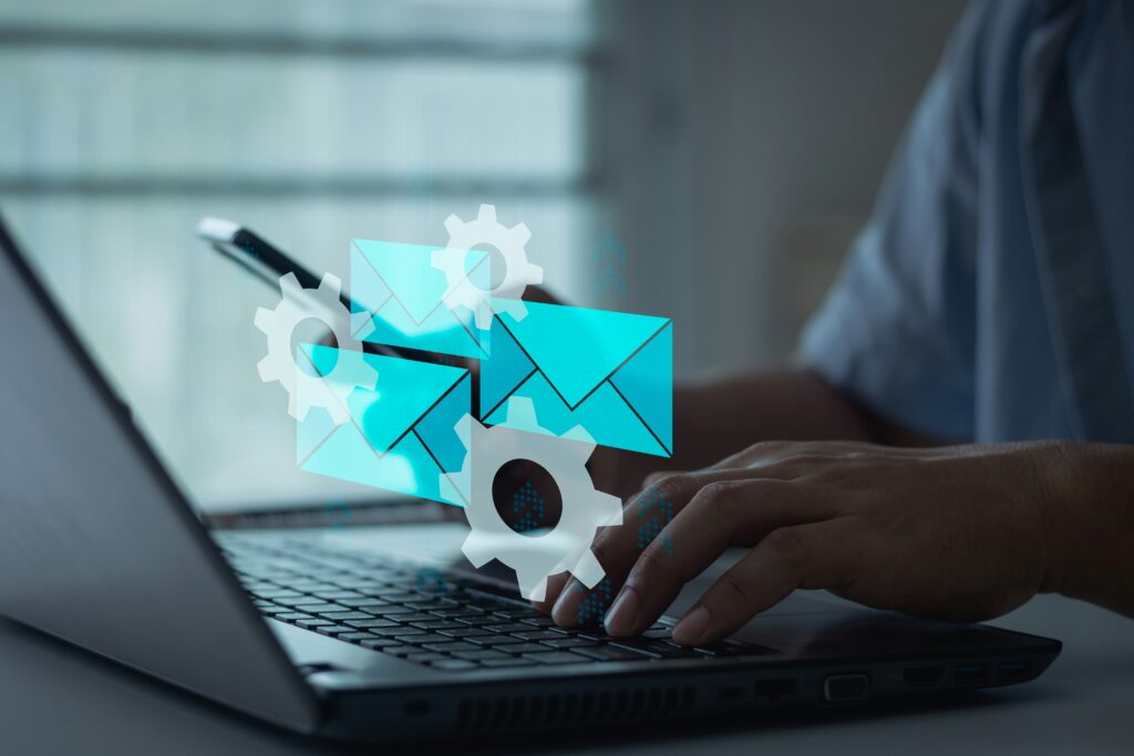 Image of a person typing on a computer with an illustration of gears and email icons hovering above his hands.